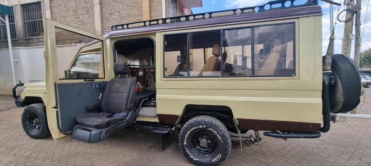 Toyota Prado 4x4 on safari in Maasai Mara with pop-up roof open during golden hour